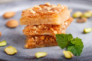 Gri beton arka planda gri seramik tabakta geleneksel Arap tatlıları. Yan görünüm, yakın görünüm, seçici odak.