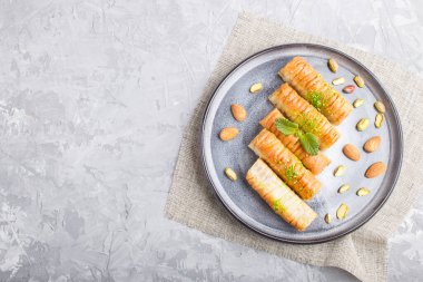 Baklava, gri beton arka planda gri seramik tabakta geleneksel Arap tatlıları. Üst görünüm, boşluk kopyala.