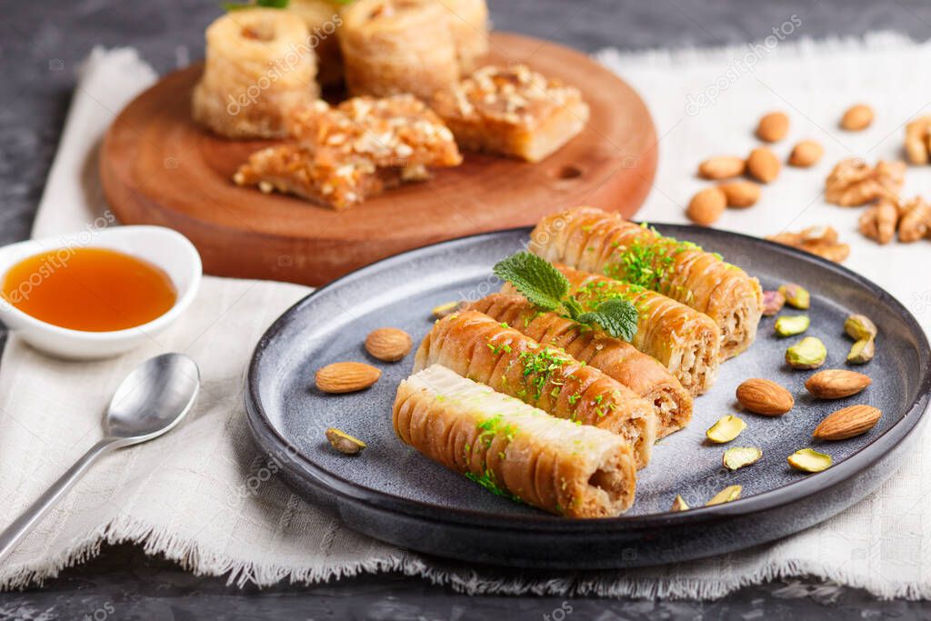 Set of various traditional arabic sweets: baklava, kunafa, basbus in  ceramic plates on a gray concrete background. side view, selective focus.