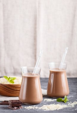 Sütsüz organik pirinç sütlü cam ve siyah beton arka planda pirinç tohumlu ahşap tabakta. Vegan sağlıklı gıda konsepti, yakın çekim, yan görüş, kopyalama alanı.