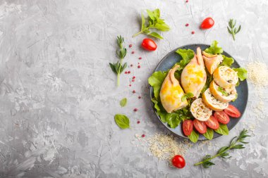 Mavi seramik tabakta yeşil mürekkep balığı ile doldurulmuş gri beton arka plan, üst manzara, düz yatış, kopyalama alanı.