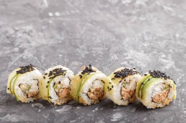 Japon maki suşisi, ton balığı, salatalık, siyah susam, siyah beton arka planda peynir. Yan görünüm, kapat, boşluğu kopyala.