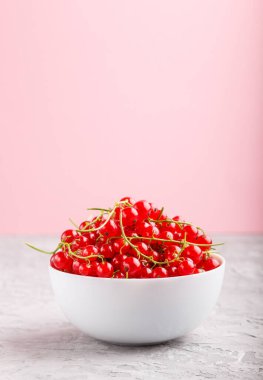 Gri ve pembe arka planda beyaz kasede taze kırmızı frenk üzümü. yan görünüm, kopyalama alanı, seçici odak.