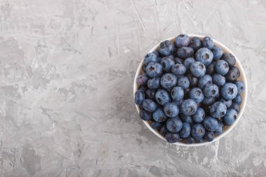 Beyaz kasede gri beton arka planda taze yaban mersini. Üst görünüm, düz görünüm, kopyalama alanı.