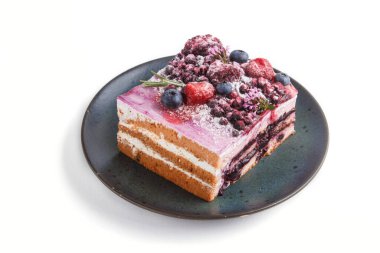 Süt kremalı ve mavi seramik tabakta yaban mersini reçelli çilekli pasta beyaz arka planda izole edilmiş. Yan görünüm, kapat.