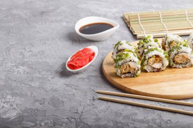 Japon maki suşisi, yeşil soğan, yemek çubuğu, soya sosu ve ahşap bir zeminde salamura edilmiş zencefil. Yan görünüm, kopyalama alanı, seçici odak.