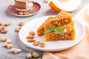 Geleneksel Türk şekerleri karamelli kavun, kavrulmuş ceviz, fındık, kaju, beyaz seramik tabakta şam fıstığı ve gri beton zemin üzerinde bir fincan kahveden yapılır. Yan görünüm, yakın görünüm, seçici odak.