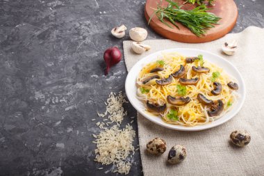 Şampiyon mantarlı pirinç eriştesi, yumurta sosu ve siyah beton arka planda beyaz seramik tabakta kekik. Yan görünüm, boşluk kopyala.