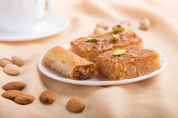 Geleneksel Arap tatlıları (basbus, kunafa, baklava) ve gri beton arka plan ve turuncu tekstil üzerinde bir fincan kahve. Yan görünüm, yakın görünüm, seçici odak, makro.