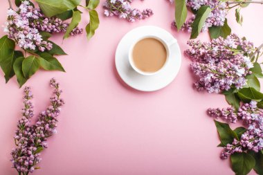 Mor leylak çiçekleri ve pastel pembe arka planda bir fincan kahve. Morninig, Spring, fotokopi alanı ile moda kompozisyonu. Düz yatış, üst görünüm.