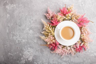 Pembe ve kırmızı astilbe çiçekleri ve gri bir arka planda bir fincan kahve. Morninig, bahar, moda kompozisyonu. Düz konum, üst görünüm, kopyalama alanı.