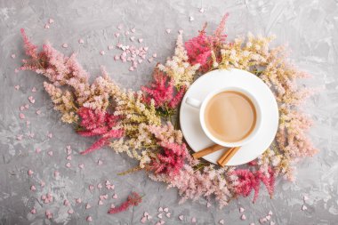 Pembe ve kırmızı astilbe çiçekleri ve gri bir arka planda bir fincan kahve. Morninig, bahar, moda kompozisyonu. Düz yatış, üst görünüm,