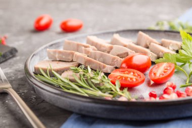 Kaynamış domuz dili, domatesli ve otlu siyah beton arka plan ve mavi keten kumaş. Yan görünüm, yakın görünüm, seçici odak.