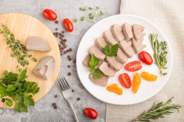 Kaynamış domuz dili, domatesli ve gri beton arka planda otlu ve keten tekstil. Üst manzara, kapat, düz yat..