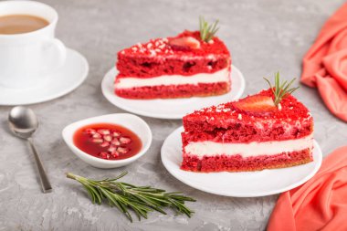 Kremalı ev yapımı kırmızı kadife kek ve kırmızı tekstil ile gri beton arka planda bir fincan kahveli çilek. Yan görünüm, yakın görünüm, seçici odak.