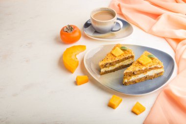 Hurma ve balkabaklı ev yapımı kek ve beyaz ahşap arka planda turuncu tekstil ile bir fincan kahve. Yan görünüm, boşluğu kopyala, kapat.