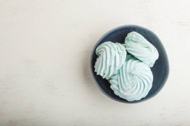 Mavi renkli ev yapımı zephyr ya da beyaz ahşap arka planda marşmelov. Üst görünüm, düz görünüm, kopyalama alanı.