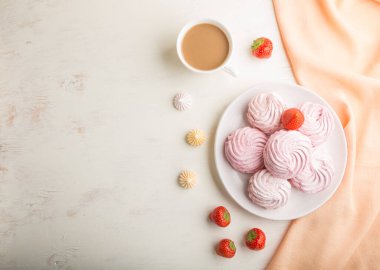 Pembe çilekli ev yapımı zephyr veya beyaz ahşap arka planda turuncu tekstil ile bir fincan kahveli marshmallow. Üst görünüm, düz görünüm, kopyalama alanı.