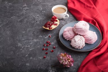 Pembe nar ev yapımı zephyr ya da koyu beton arka planda kırmızı tekstil ile bir fincan kahveli marshmallow. Yan görünüm, boşluğu kopyala, kapat.