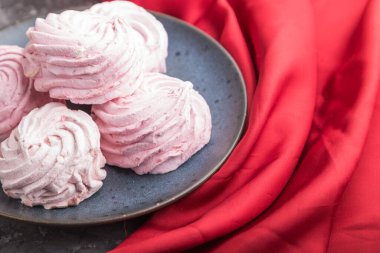 Pembe nar ev yapımı zephyr ya da kırmızı tekstil ile siyah beton arka planda marşmelov. Yan görünüm, yakın görünüm, seçici odak.