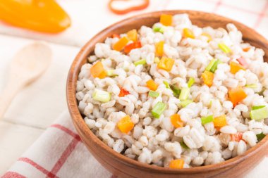 Tahta kasede sebzeli inci arpa lapası beyaz ahşap arka plan ve keten tekstil. Yan görüş, seçici odaklanma. Rus geleneksel mutfağı.