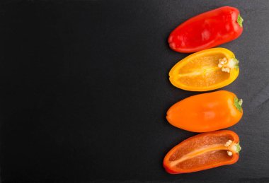 Sarı, kırmızı, turuncu tatlı biberler siyah bir arkaplanda. Üst görünüm, kopyala boşluk, düz görünüm, kapat.