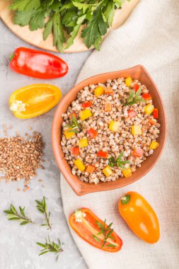 Kil kasede sebzeli karabuğday lapası gri beton arka plan ve keten tekstil. Üst manzara, düz yatak, yakın çekim. Rus geleneksel mutfağı.