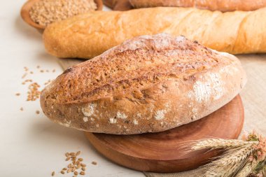 Beyaz ahşap arka planda farklı pişmiş ekmek türleri. Yan görünüm, yakın görünüm, seçici odak.