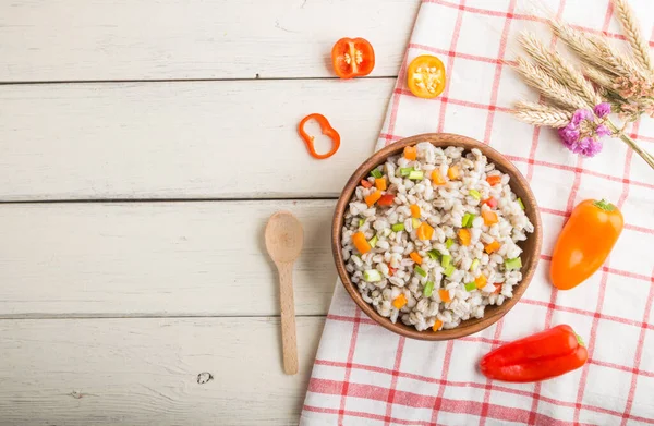 Tahta kasede sebzeli inci arpa lapası beyaz ahşap arka plan ve keten tekstil. Üst görünüm, düz görünüm, kopyalama alanı. Rus geleneksel mutfağı.