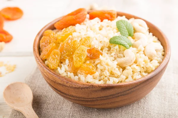 Gachas Bulgur Con Albaricoques Secos Pasas Anacardo Cuenco Madera Sobre — Foto de Stock