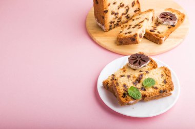 Kuru üzümlü ev yapımı kek ve pembe pastel arka planda kurutulmuş hurma. Yan görünüm, kapat, boşluğu kopyala.