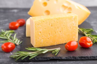 Biberiyeli çeşitli peynirler ve siyah tahta üzerine siyah beton kaplama domatesler. Yan görünüm, yakın görünüm, seçici odak.