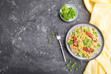 Yeşil bezelye, mısır ve kurutulmuş domatesli kinoa lapası gri beton arka planda seramik tabak ve sarı tekstil. Üst görünüm, düz görünüm, kopyalama alanı.