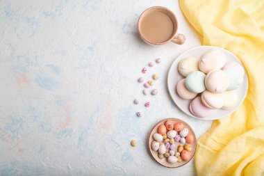 Renkli zephyr veya bir fincan kahveli marşmelov ve beyaz beton arka plan ve sarı tekstil üzerine sürükleyici. Üst görünüm, düz görünüm, kopyalama alanı.