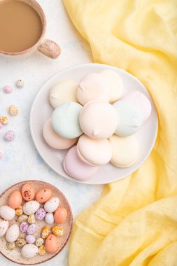 Renkli zephyr veya bir fincan kahveli marşmelov ve beyaz beton arka plan ve sarı tekstil üzerine sürükleyici. Üst görünüm, düz görünüm, yakın çekim.