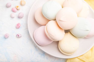 Renkli zephyr ya da marşmelov ve beyaz beton arka plan ve sarı tekstil üzerindeki sürükleyiciler. Üst görünüm, düz görünüm, yakın çekim.