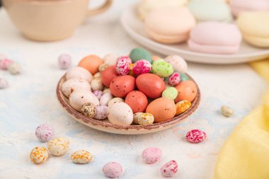 Beyaz beton arka plan ve sarı tekstil üzerinde kahve fincanı olan renkli elbiseler. Yan görünüm, yakın görünüm, seçici odak.