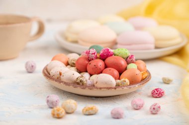 Beyaz beton arka plan ve sarı tekstil üzerinde kahve fincanı olan renkli elbiseler. Yan görünüm, yakın görünüm, seçici odak.