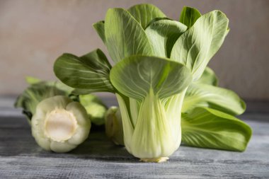 Taze yeşil bok choy ya da gri ahşap arka planda Çin lahanası. Sert ışık, kontrast. Yan görünüm, yakın görünüm, seçici odak.