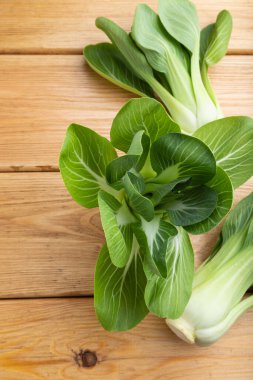 Kahverengi ahşap arka planda taze yeşil bok choy veya pac choi Çin lahanası. Üst manzara, kapat, düz yat..