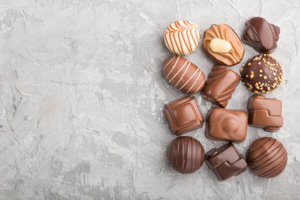 Different chocolate candies on a gray concrete background. top view, flat lay, copy space.
