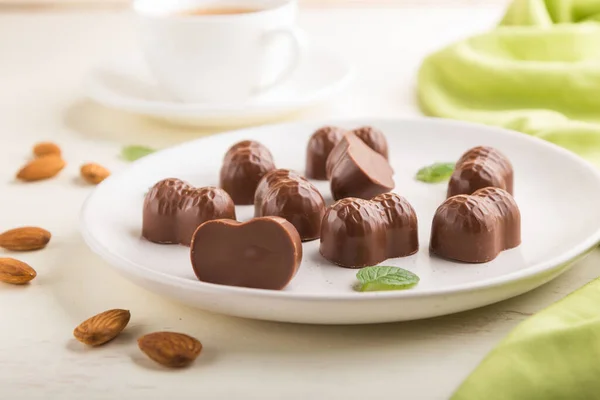 Caramelle Cioccolato Con Mandorle Una Tazza Caffè Sfondo Bianco Legno — Foto Stock