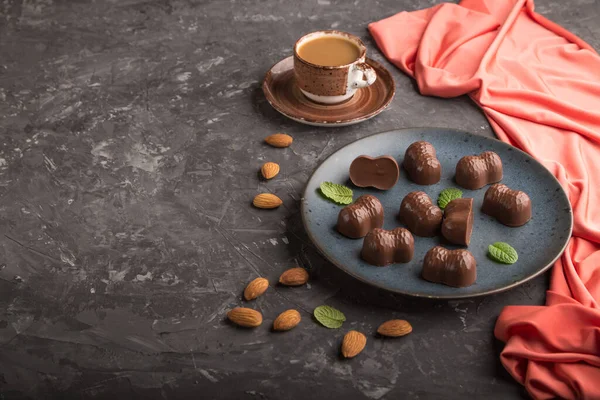 Caramelle Cioccolato Con Mandorle Una Tazza Caffè Uno Sfondo Cemento — Foto Stock