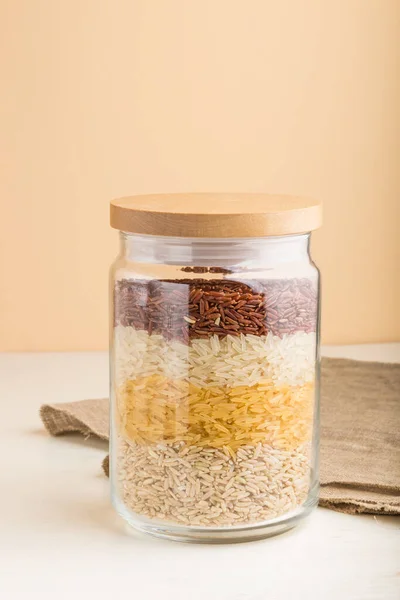 Glass Jar Different Kinds Rice Poured Layers White Orange Background — Stock Photo, Image