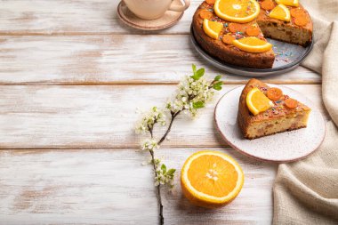 Turuncu kek ve beyaz ahşap arka planda bir fincan kahve ve keten tekstil. Yan görünüm, boşluk kopyala.
