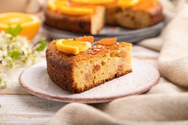 Turuncu kek ve beyaz ahşap arka planda bir fincan kahve ve keten tekstil. Yan görünüm, yakın görünüm, seçici odak.