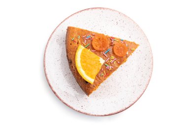 Beyaz arka planda izole edilmiş seramik tabakta turuncu kek. Üst görünüm, kapat