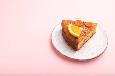 Pastel pembe arka planda bir parça turuncu pasta. Yan görünüm, kopyala boşluk, kapat.