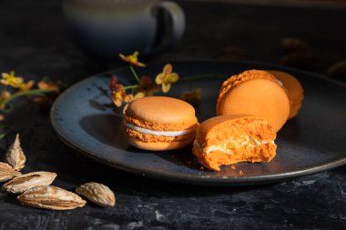 Siyah beton arka planda bir fincan kahveyle portakallı kurabiyeler veya kurabiyeler. Sert ışık, kontrast, düşük tuş. Yan görünüm, kapat.