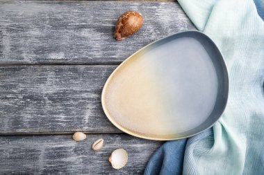 Gri ahşap arka planda boş mavi seramik tabak ve mavi tekstil. Üst görünüm, kopyalama alanı, düz uzanma.